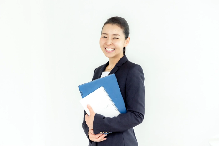 ファイルケースを持って立つスーツ姿の工藤倫子